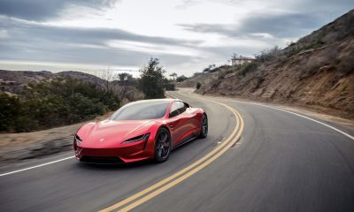 A red Tesla Roadster driving around a turn