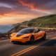 Tesla Roadster driving along sunset cliff (Credit: Grok)
